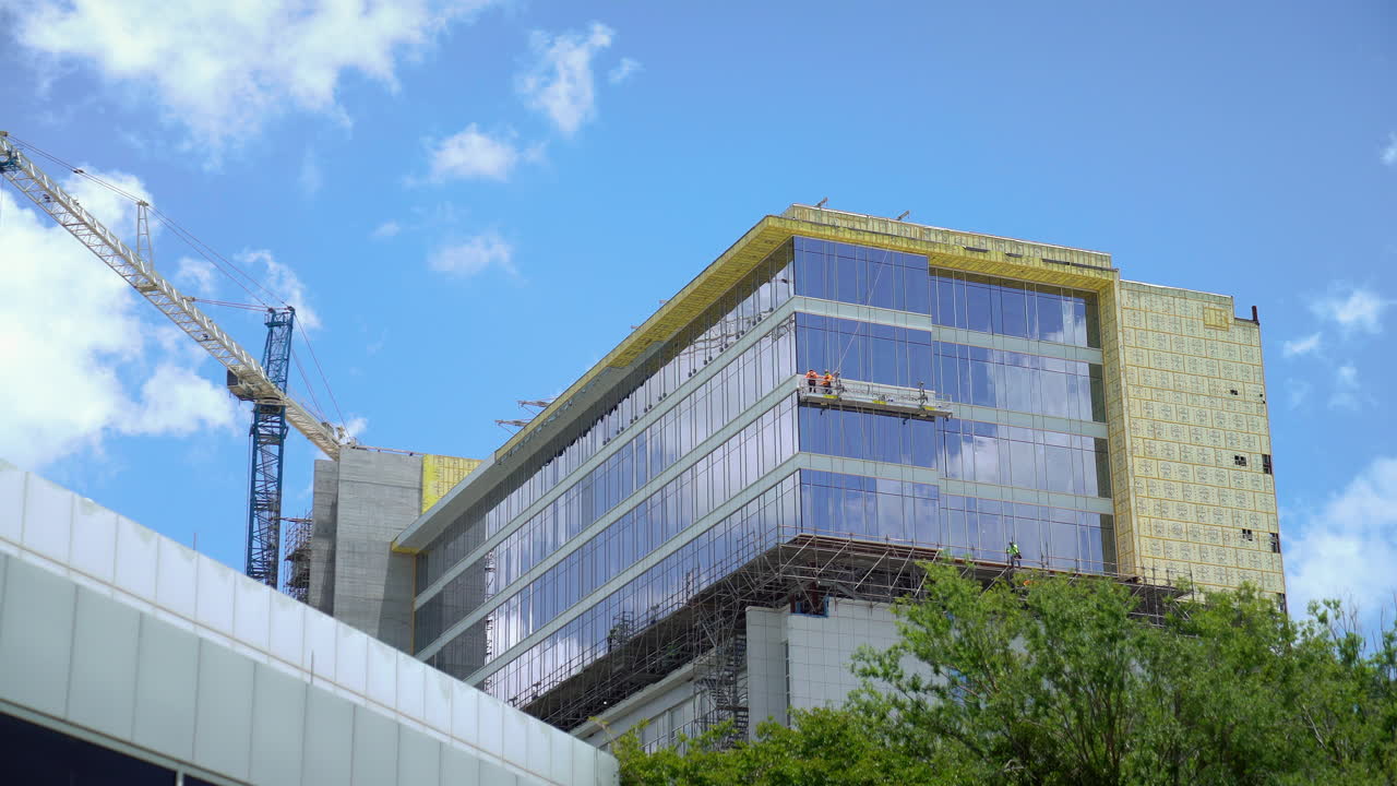 A time lapse showing the progress of a building under construction. The footage captures the transformation of the site as workers and machines move swiftly, with clear skies and changing lighting.