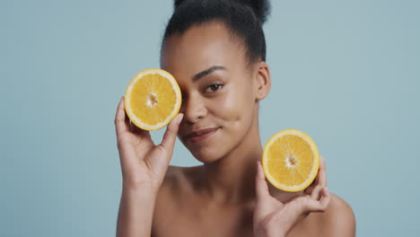 portrait attractive young african american woman holding lemon smiling enjoying natural healthy skincare essence beautiful female with perfect complexion on blue background