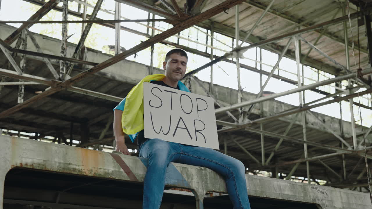 Protestor holding a sign reading 'Stop War' in an abandoned factory