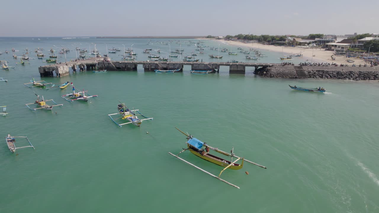 Aerial view of Indonesian traditional juking boat departing to the sea from the beach on turquoise transparent waves near a tropical island of Bali. The concept of an exotic vacation and culture.