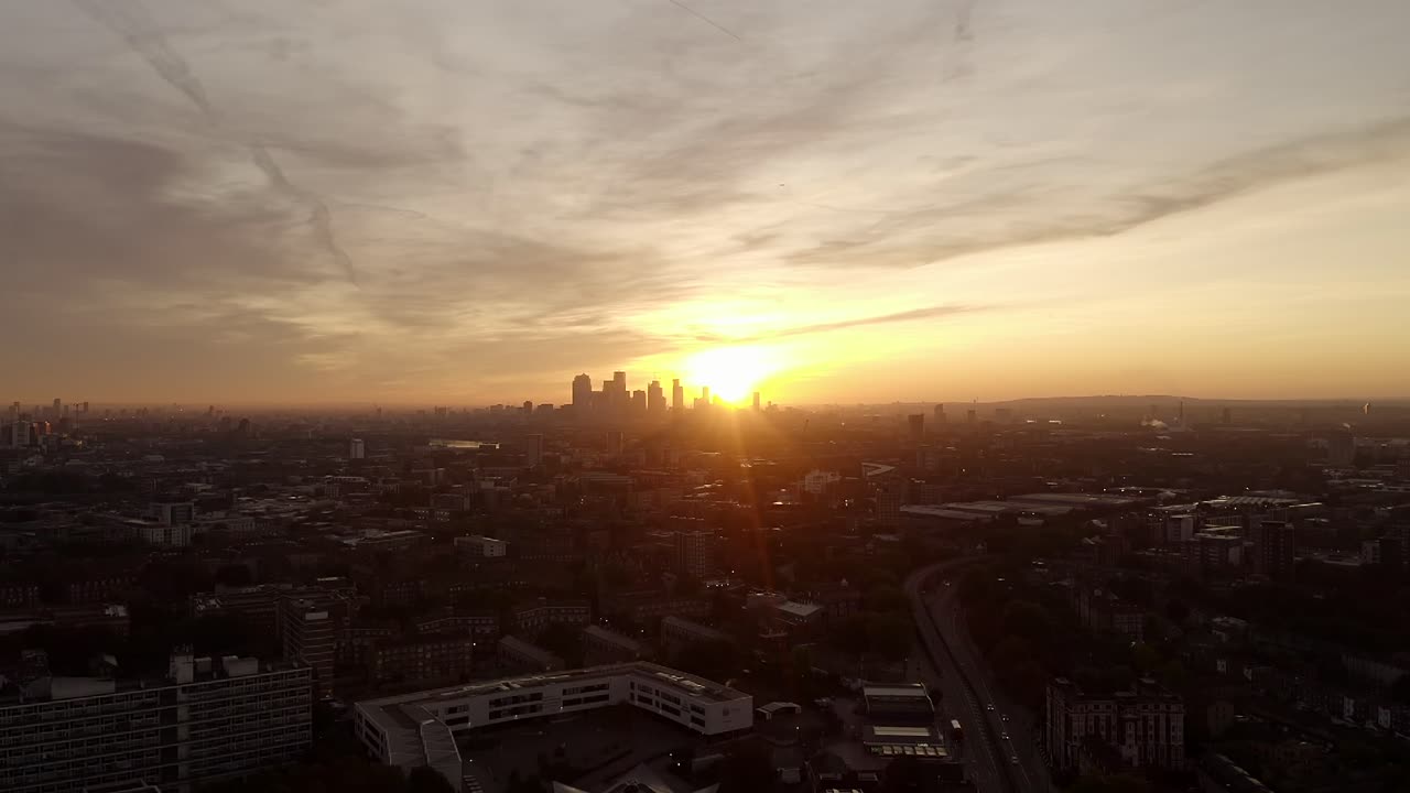 Vídeo mostra a paisagem do nascer do sol em Londres. Os raios de sol brilham através dos arranha-céus e iluminam a cidade numa manhã nevoenta.