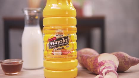 philippines - a lauric oil in a bottle, sweet potatoes, white vinegar and fish sauce, preparing ingredients for cooking - close up pull shot