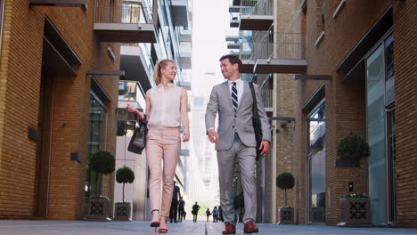 businessman and businesswoman walk to work along city street