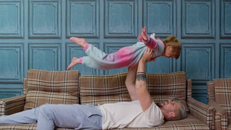 Child-girl-playing-game-laughing-having-fun-with-father,-happy-dad-lifting-small-kid-daughter-up