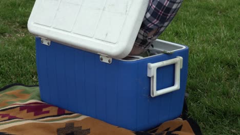 man going through a blue cooler at a picnic