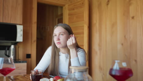 two women enjoy relaxed chat in cozy wooden room, one gesturing while talking, another thoughtfully listening, red drink on table adding vibrant color