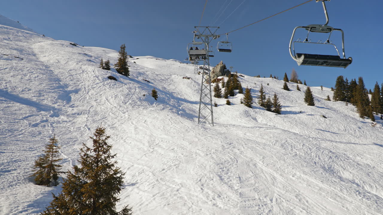 Ripresa POV seduti su una seggiovia che sale la montagna a LAAX. Splendide viste alpine, tranquilla atmosfera invernale e un'autentica esperienza da stazione sciistica in una giornata limpida