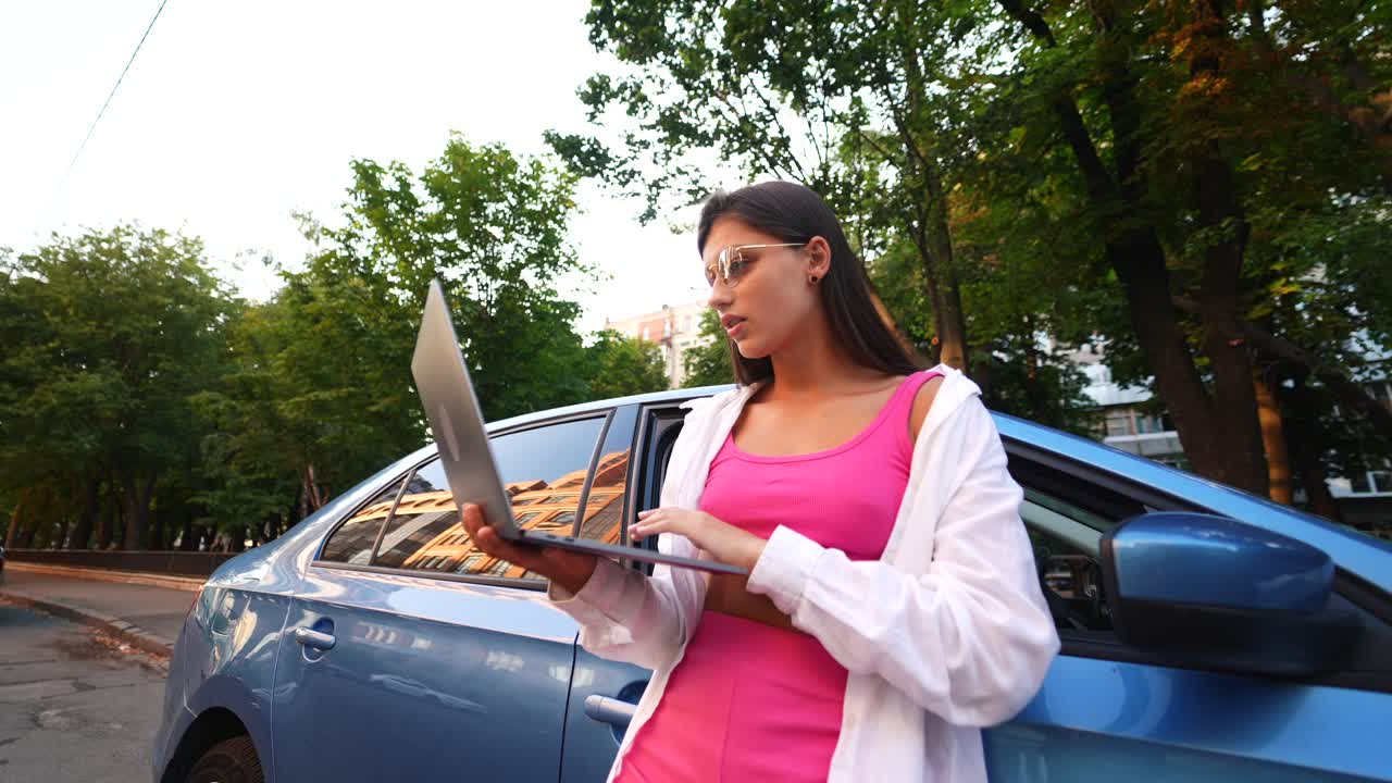 joven trabajando en una computadora portátil por un coche azul