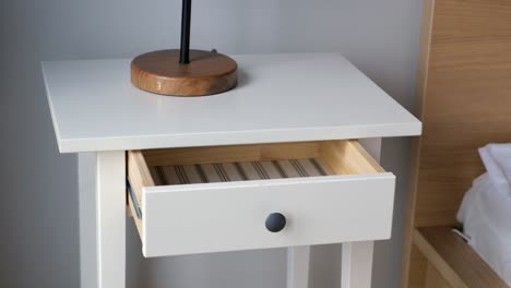 white nightstand with open drawer and lamp