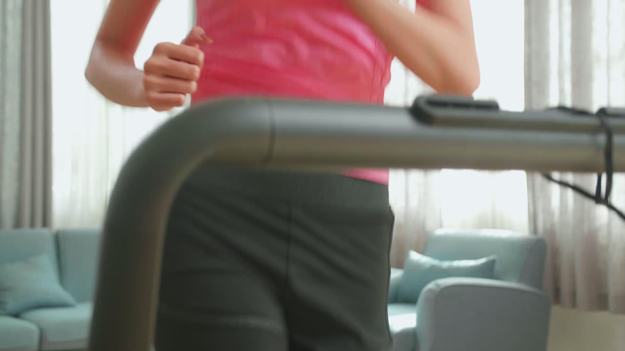 Front View Of Asian Woman Running On A Treadmill At Home