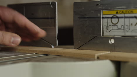 Close-up-of-a-carpenter-using-a-chop-saw-to-cut-a-wooden-plank