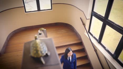 Asiatische-Studentin-Steigt-In-Zeitlupenaufnahme-Von-Oben-Die-Treppe-Hinunter