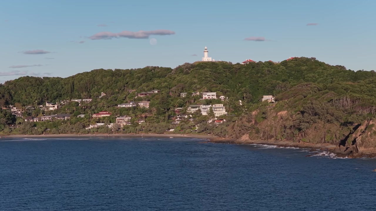 Popolare zona costiera di Wategos Beach e il faro di Cape Byron a Byron Bay, Nuovo Galles del Sud, Australia. Ripresa aerea ruotata.