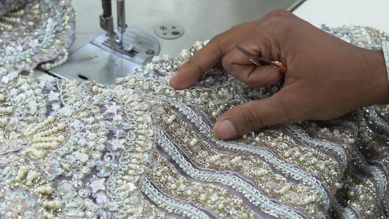 Close Up Shot Of A Dressmaker Using Scissors During Beadwork Process Of Manufacturing Pakistani Clothing.