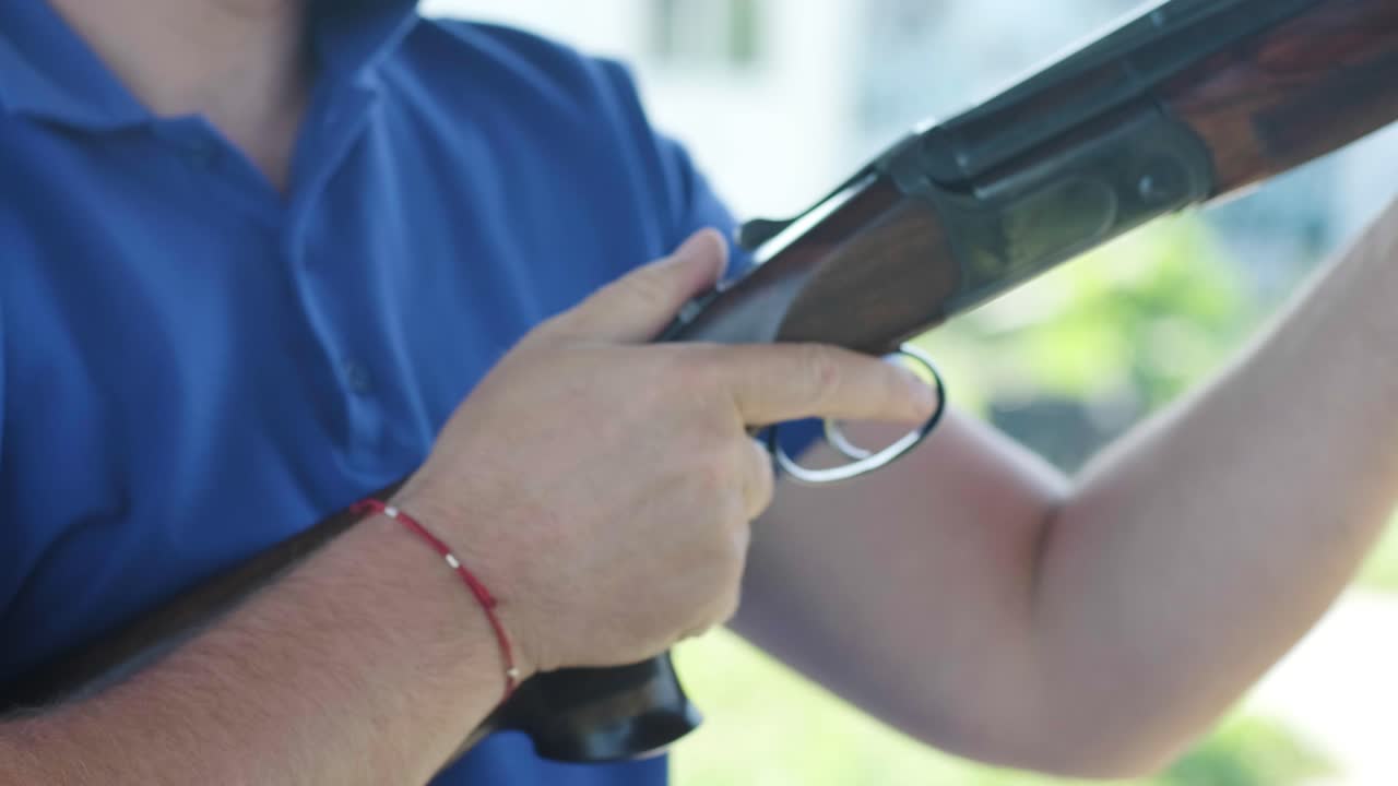 스포츠맨이 이중 배럴 건으로 총을 고, 슈팅 테스트를 위한 스포츠 경기장은 날아다니는 스케이트를 고 있습니다.