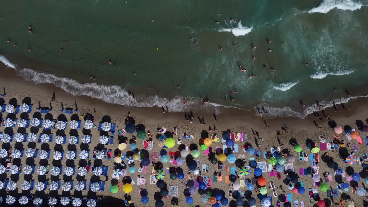 vista de pájaro de la gente en una playa concurrida en verano con sombrillas y el mar