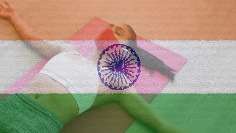 animation of woman wearing face mask practicing yoga over indian flag