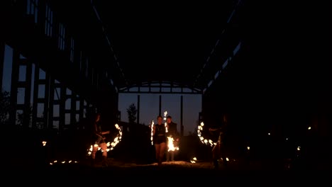 a group of people with fire and torches dancing at sunset in the hangar in slow motion. fire show