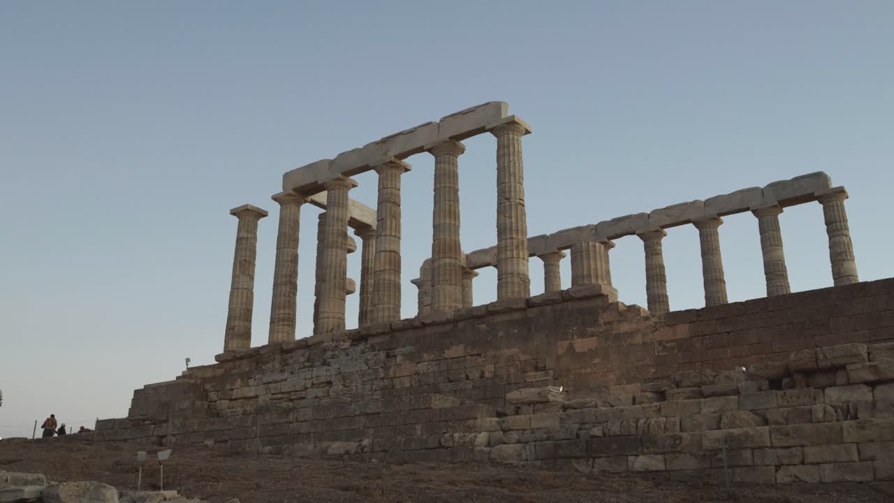 Push-in toward Temple of Athena Sounias with stone pillars at sunset