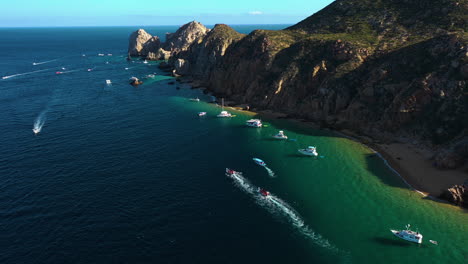 Vista-Aérea-Siguiendo-Los-Barcos-En-El-Arco-De-Cabo-San-Lucas,-Día-Soleado-En-México