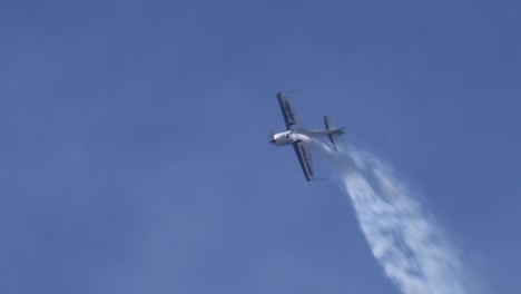 el avión ejecuta maniobras complejas en un cielo azul despejado