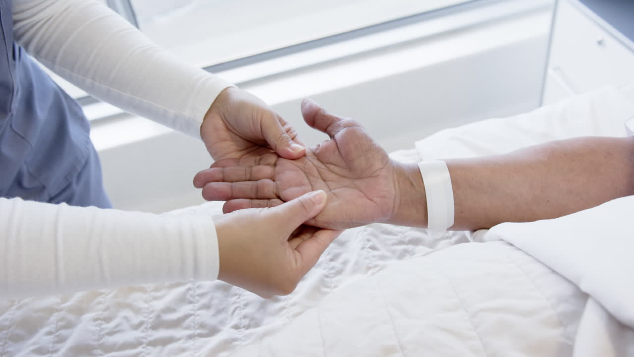 diversa mujer médico probando la mano de una anciana paciente en la habitación del hospital, cámara lenta