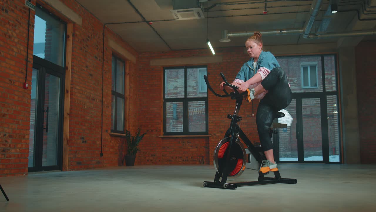 mujer atlética montando en bicicleta estacionaria rutina de entrenamiento en gimnasio de neblina, pérdida de peso en interiores