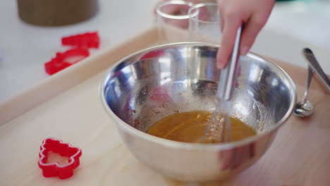 young boy mixes egg and spices in metal bowl