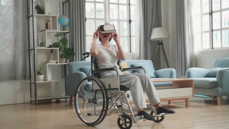mujer asiática sentada en una silla de ruedas mientras usa gafas de realidad virtual en casa