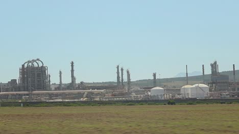 driving by a gas and oil refinery, visible in the distance