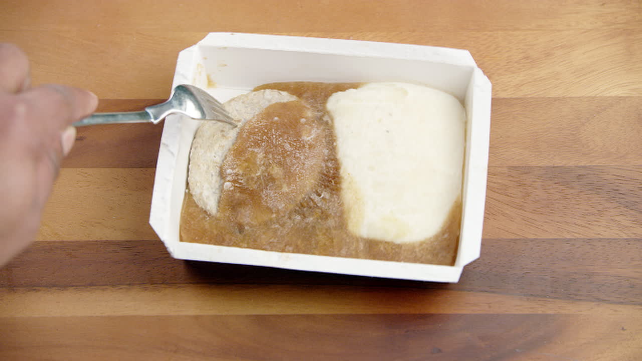 흰색 사용 및 던지기 용기에서 포크로 냉동 식품 얼음 식사를 깨려고 합니다.