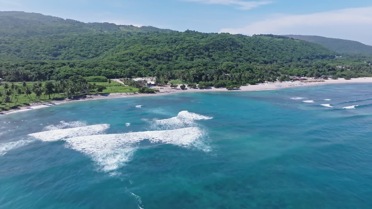 olas chocando contra el complejo de playa de arena tropical en el quemaito, avión no tripulado hacia adelante
