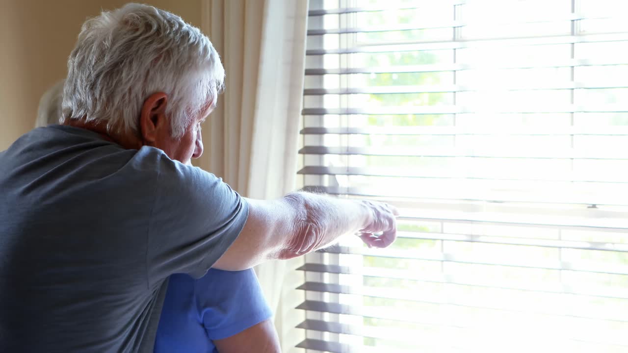 시니어 커플이 창문을 통해 쳐다보며 이야기하고 있습니다.