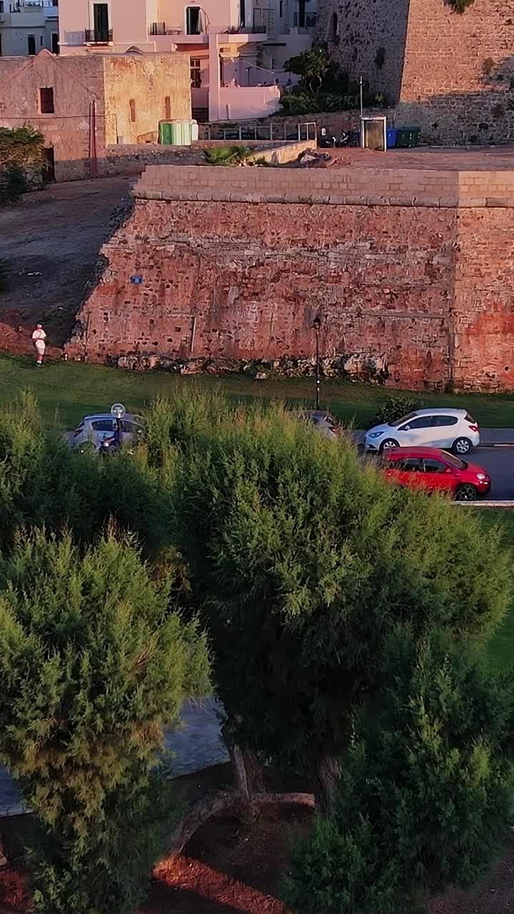 Vista aerea di una città storica con antiche mura in pietra e parco all'ora d'oro