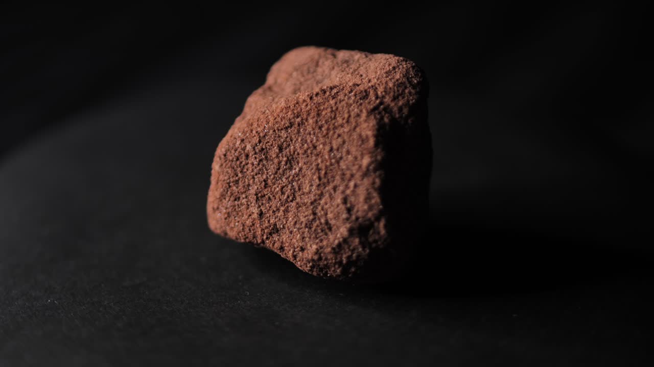 Dark Studio Lighting Highlights Rotating Red Stone from Grand Canyon
