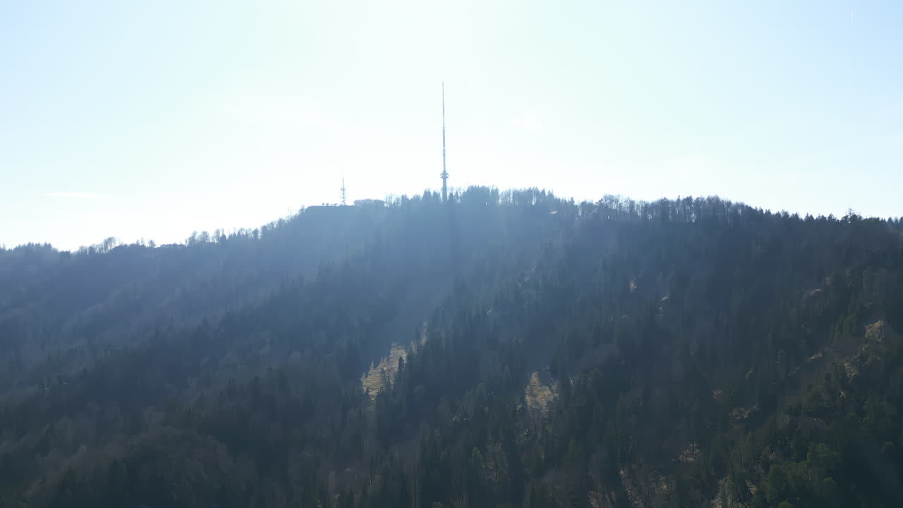 Crane up drone shot of Uetliberg TV Tower with sun shining during the day in Zurich, Switzerland