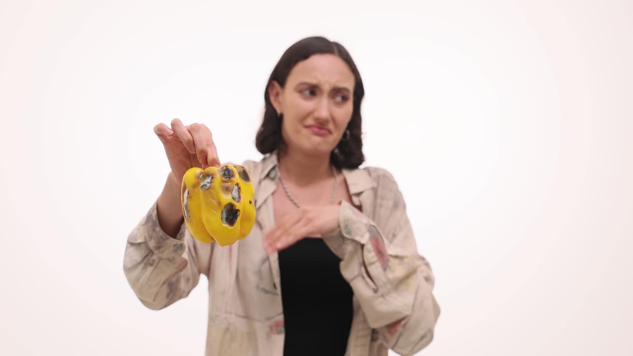 Woman reacts with disgust to a rotten, moldy bell pepper