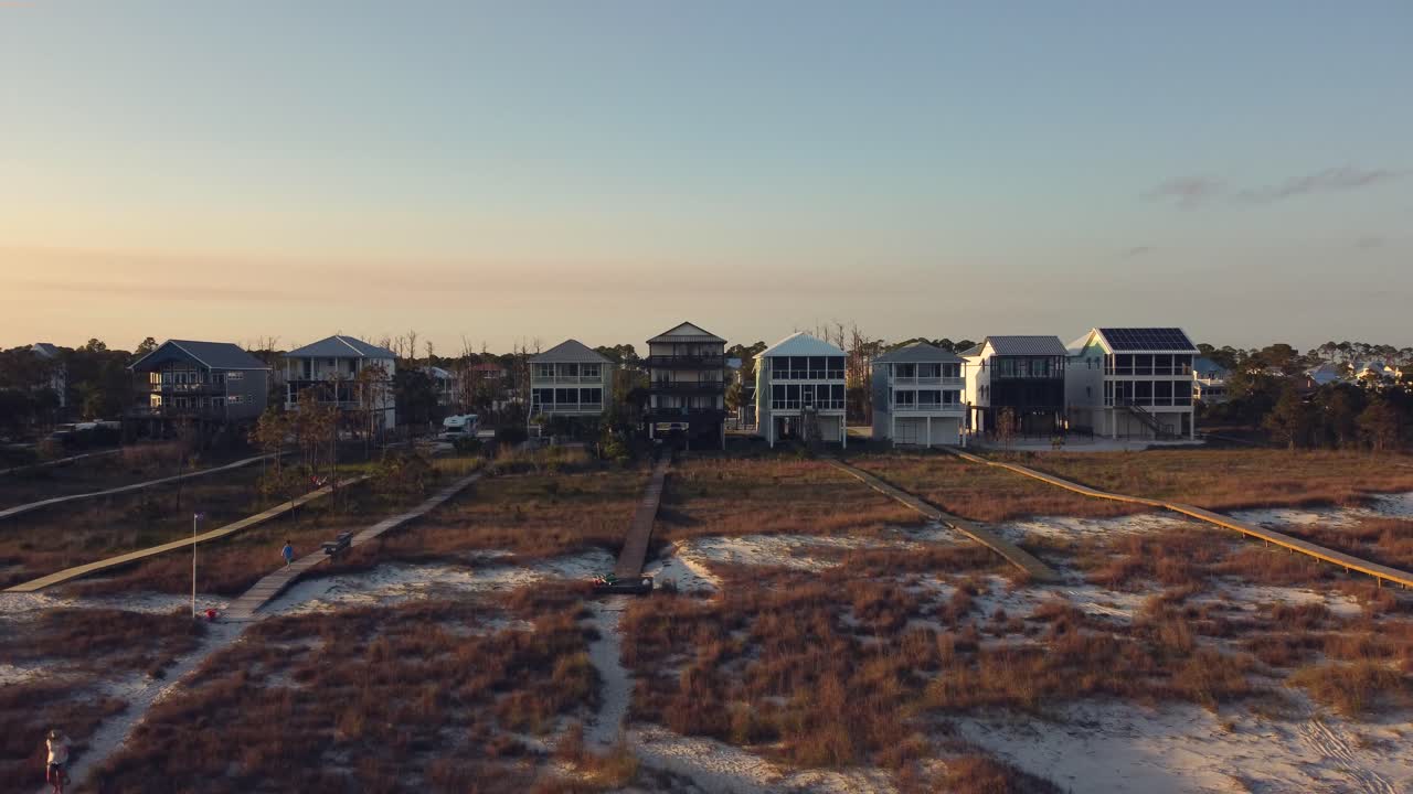 Aerial drone footage of Florida vacation home on the beach in the summer during sunset. Access to sandy and sunny beach via boardwalk.