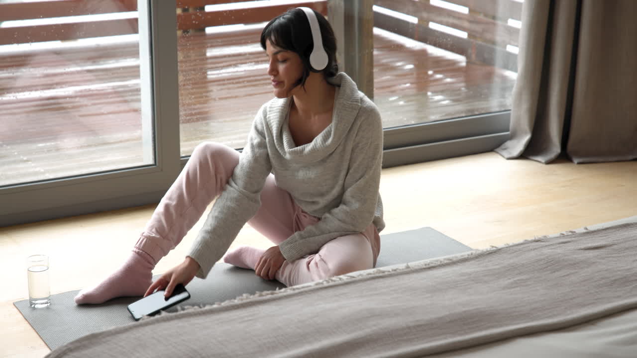 Relaxing at home, woman meditating with headphones on yoga mat