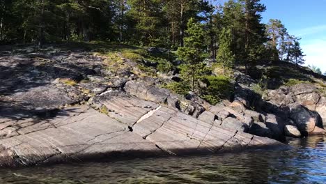 Rocky-shores-in-Karelia,-Russia-with-crystal-clear-blue-water-and-green-surroundings