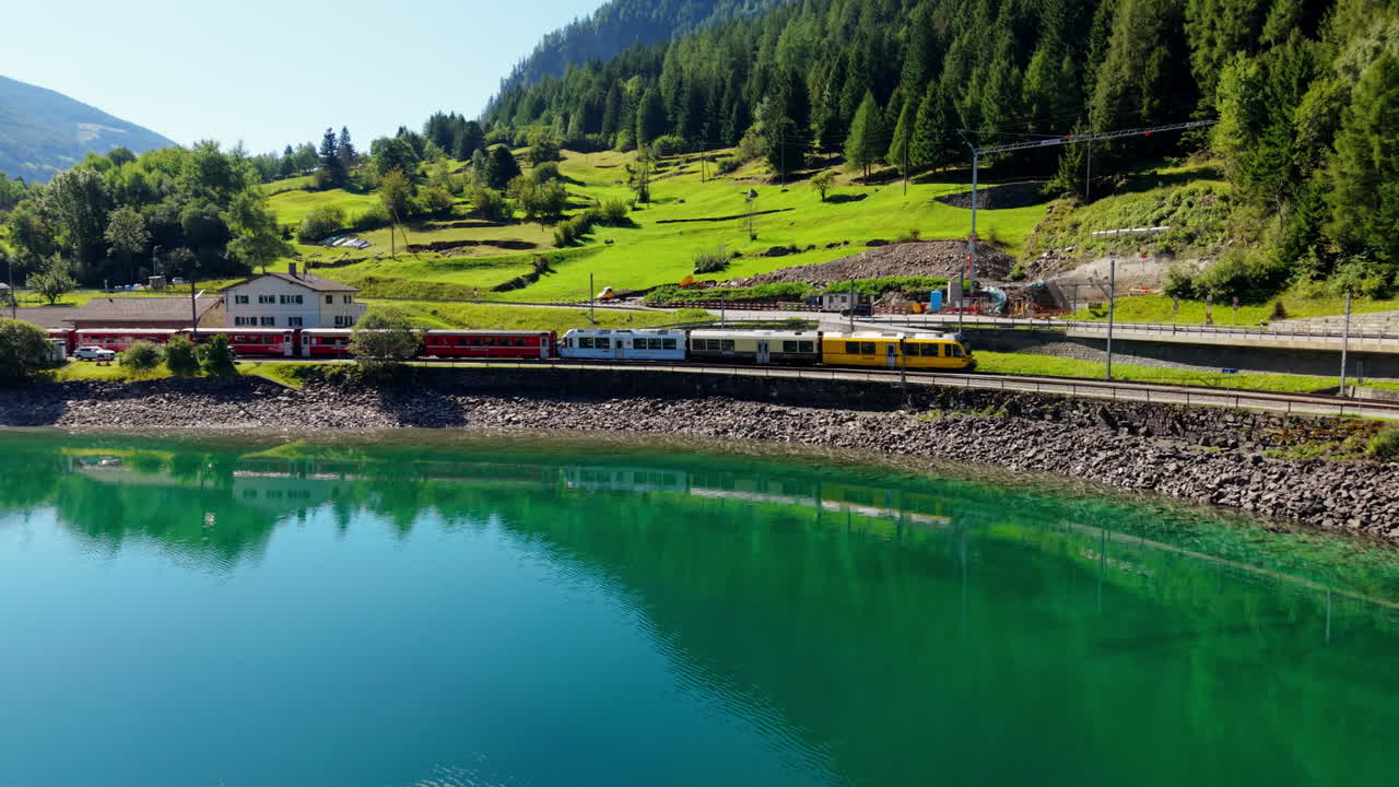 Scenic train in Swiss mountains with lake view in vibrant summer day