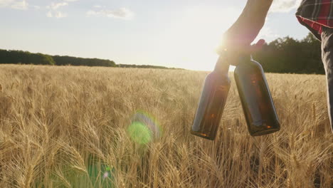 a man with two bottles of beer walks along a wheat field