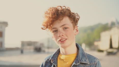 red haired teenager with freckles looks directly into the camera