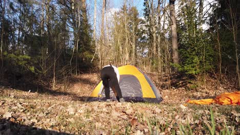 girl in a hood built a tent in the woods alone in a campsite - medium shot, slow motion