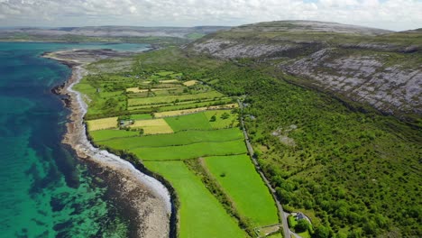 small road through rural landscape and coastline in west ireland, forward aerial