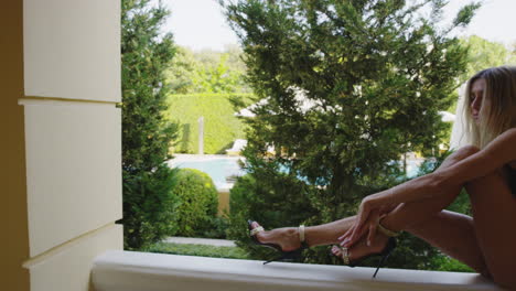 modern female model wearing an elegant shoes and bikini in a balcony of hotel