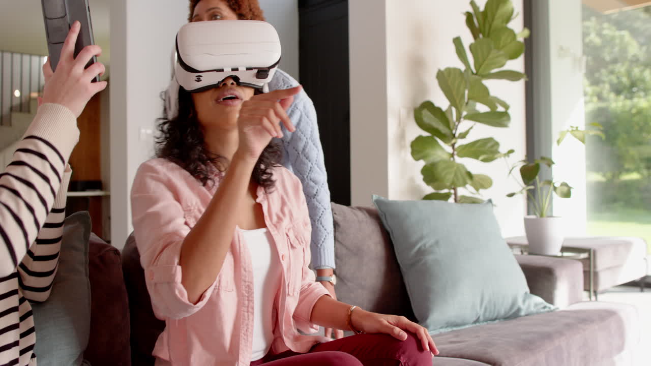 Using VR headset, woman sitting on couch with female friends taking selfie