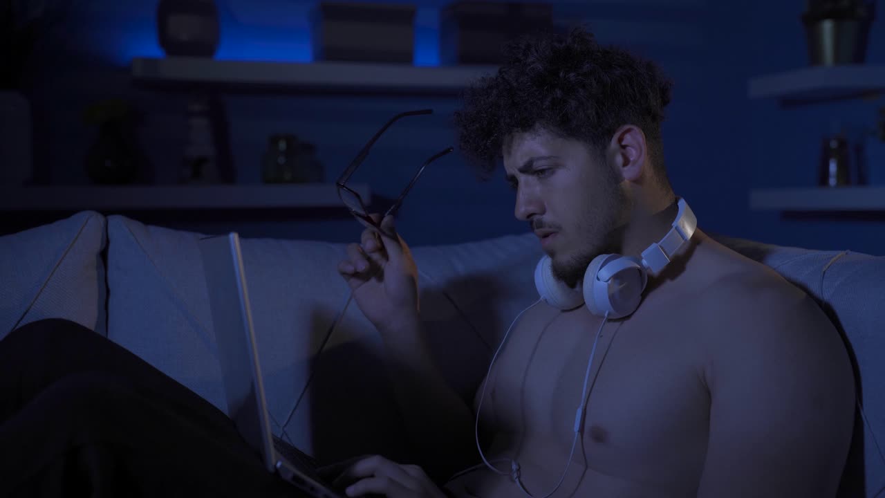 un joven serio y concentrado mirando la computadora portátil.