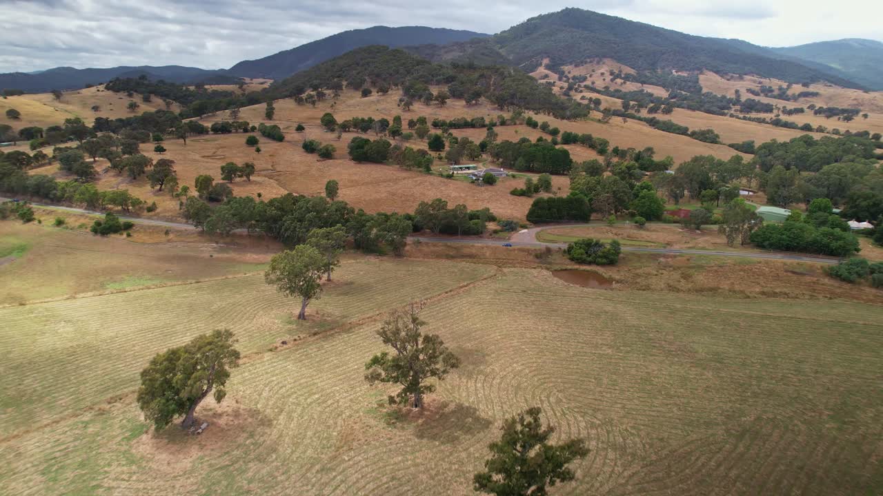 sobre árboles en prados hacia una carretera con una granja en el fondo cerca de eildon, victoria, australia
