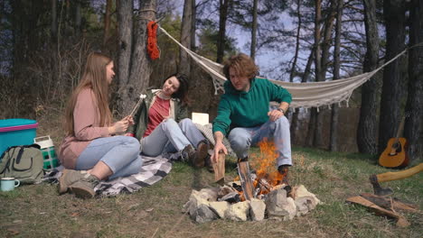 two young girls and a young boy make a bonfire in the forest